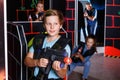 Excited boy aiming laser gun at other players during laser tag game in dark room Royalty Free Stock Photo