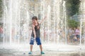 Excited boy having fun between water jets, in fountain. Summer i