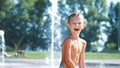 excited boy of seven years having fun between water jets, in fountain, run around, sprinkle, have fun, have fun, on a