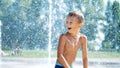 excited boy of seven years having fun between water jets, in fountain, run around, sprinkle, have fun, have fun, on a