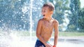 excited boy of seven years having fun between water jets, in fountain, run around, sprinkle, have fun, have fun, on a