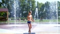 Excited boy of seven years having fun between water jets, in fountain, run around, sprinkle, have fun, have fun, on a