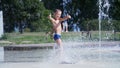 Excited boy of seven years having fun between water jets, in fountain, run around, sprinkle, have fun, have fun, on a