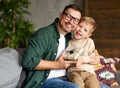 Excited boy son giving gift box for young loving father on holiday while sitting together on sofa Royalty Free Stock Photo