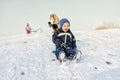 Excited little boy on snow tobogganing Royalty Free Stock Photo