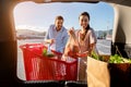 Excited brazilian spouses packing shopping bags with fresh food into the car trunk, view from the vehicle interior Royalty Free Stock Photo