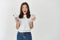 Excited brunette woman showing credit card and using mobile phone, shopping online, standing happy at camera, standing Royalty Free Stock Photo