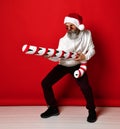 Excited brutal man in santa hat shooting from candy cane