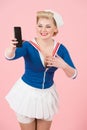 Excited bug eyed young blonde female wearing sailor shirt and headband with smiling face emotion pointing at cell phone. Royalty Free Stock Photo