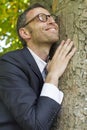 Excited businessman hugging a tree for vitality and energy