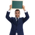 Excited businessman in navy blue suit holding blackboard above head