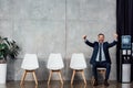 Excited businessman in suit sitting and showing thumbs up in Royalty Free Stock Photo