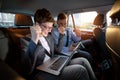 Excited businesspeople looking at laptop in car on trip Royalty Free Stock Photo