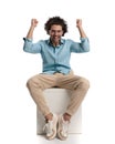 excited casual man celebrating while sitting on box Royalty Free Stock Photo
