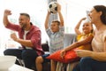 Excited caucasian parents on couch with daughter and son watching football match on tv and cheering