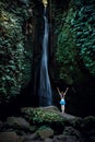 Excited Caucasian woman raising arms in front of waterfall. View from back. Leke Leke waterfall, Bali, Indonesia Royalty Free Stock Photo