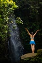 Excited Caucasian woman raising arms in front of waterfall. View from back. Near Tegenungan waterfall. Ubud, Bali, Indonesia Royalty Free Stock Photo