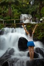 Excited Caucasian woman raising arms in front of waterfall. View from back. Jembong waterfall. Singaraja, Bali, Indonesia Royalty Free Stock Photo