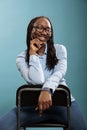 Excited cheerful african american pretty attractive woman sitting on chair while smiling at camera Royalty Free Stock Photo