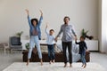 Excited cheerful African parents and little kids jumping on carpet Royalty Free Stock Photo