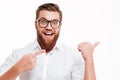 Excited cheerful bearded man in eyeglasses pointing away