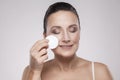 Excited cheerful confident lovely beautiful mature woman is using a cotton pad with micellar water for removing make up from face Royalty Free Stock Photo