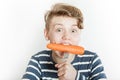 Excited child biting into large carrot