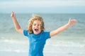 Excited child funny face. Cute kid run and raised hand on summer sea. Funny expressive emotional boy running on summer Royalty Free Stock Photo
