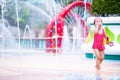 Excited child girl having fun between water splashes in fountain courtyard. Summertime in city. In hot day. Kid aged 3-4 years old Royalty Free Stock Photo