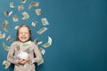Excited child girl standing with arm folded in money rain and screaming with joy. Concept of sudden enrichment