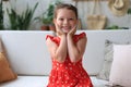 Excited child looking at camera while sitting in living room at home