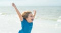 Excited child running in the summer sea. Cute kid run on summer sea. Funny expressive emotional boy running on summer