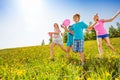 Excited children with balloons run in green field Royalty Free Stock Photo