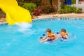 Excited children in water park riding on slide with float Royalty Free Stock Photo