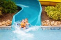 Excited children in water park riding on slide with float Royalty Free Stock Photo