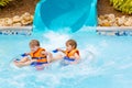 Excited children in water park riding on slide with float Royalty Free Stock Photo