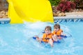 Excited children in water park riding on slide with float Royalty Free Stock Photo