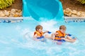 Excited children in water park riding on slide with float Royalty Free Stock Photo