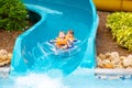 Excited children in water park riding on slide with float Royalty Free Stock Photo