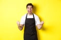 Excited coffee shop owner in black apron celebrating, making fist pump and shouting for joy, achieve goal, standing