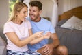 Excited Couple In Bedroom At Home Celebrating Positive Pregnancy Test Result Royalty Free Stock Photo