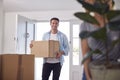 Excited Couple Carrying Boxes And Plant Through Front Door Of New Home On Moving Day Royalty Free Stock Photo