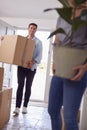 Excited Couple Carrying Boxes And Plant Through Front Door Of New Home On Moving Day Royalty Free Stock Photo