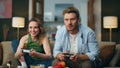 Excited couple competing videogame at home. Nasty man taking gamepad from woman Royalty Free Stock Photo