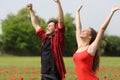 Excited couple raising arms on a poppy field