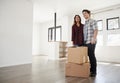 Excited Couple Standing With Boxes In New Home On Moving Day