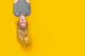 Excited crazy little blonde girl hanging happy upside down over isolated yellow studio background. Emotion, expression Royalty Free Stock Photo