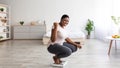 Excited curvy black woman sitting on scales at home, making YES gesture, happy with result of her slimming diet