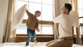 Excited cute daughter playing pillow fight on bed with father Royalty Free Stock Photo