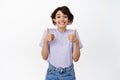 Excited cute girl showing thumbs up, being supportive, smiling at camera, white background Royalty Free Stock Photo